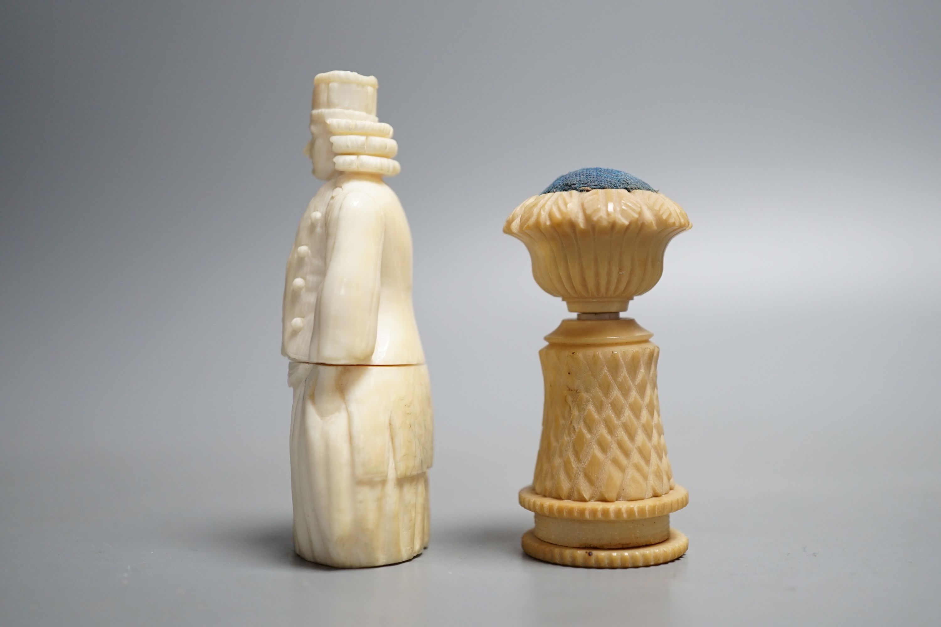 A Dieppe ivory figural needle case, vegetable ivory sewing tape and pin cushion, 19th century